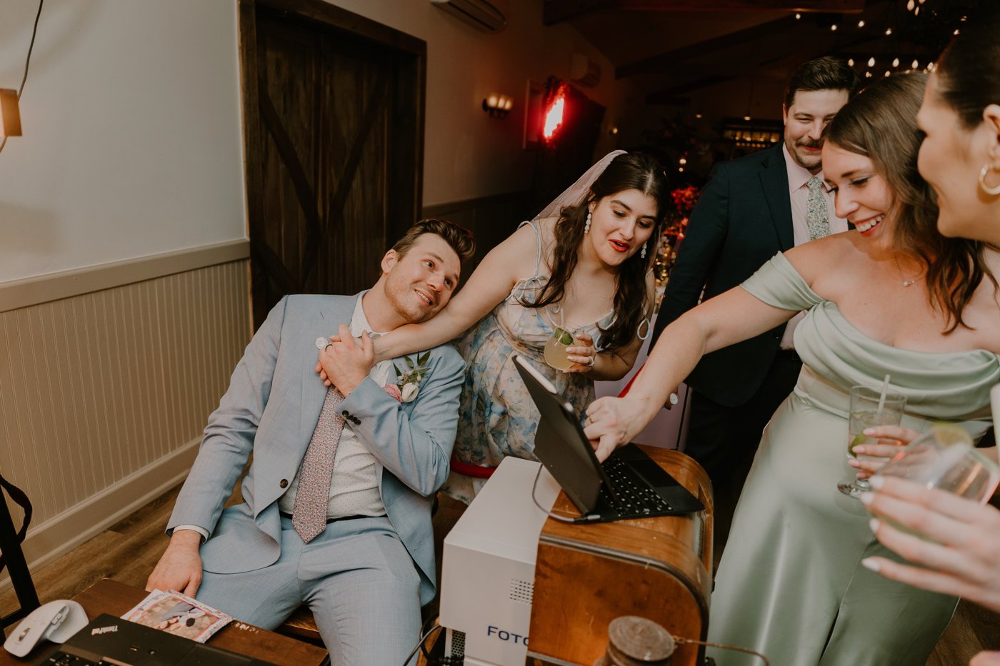 Mark operating the Copper&Velvet photobooth at his own wedding reception, surrounded by guests looking at the tablet.